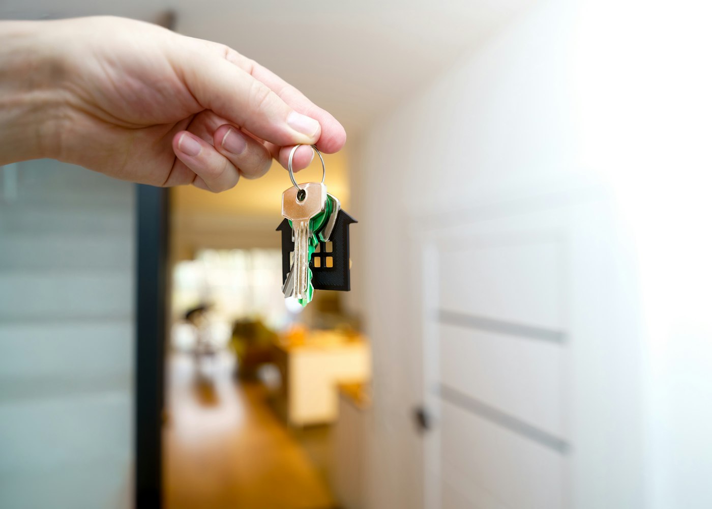 A hand holding house keys in the doorway of a new home